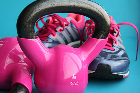 close up photo of pink and black kettlebell and running shoes