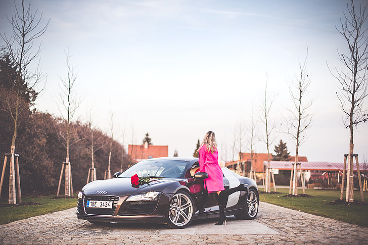 Woman in Pink Coat Standing Next To a Supercar