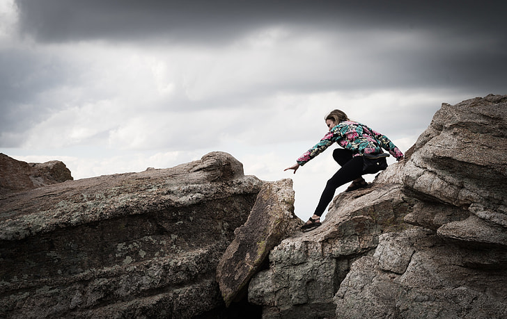 woman in black pants climbing rocks