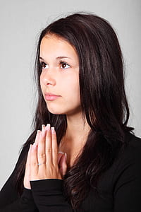 girl wearing black long-sleeved shirt praying