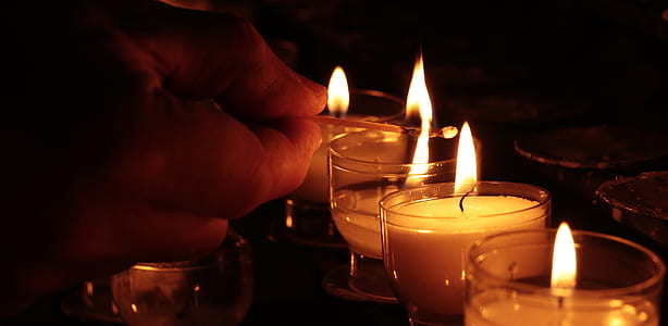 person lighting votive candles