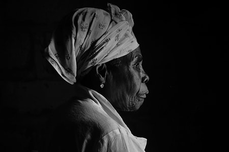 photo of woman with headwrap and white top with black background portrait