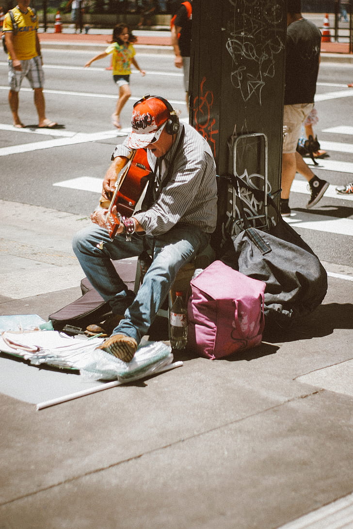man playing guitar on street during daytime