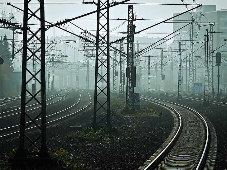 photo of black train rail surrounded by transmission towers