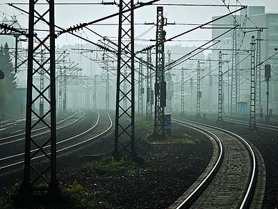 photo of black train rail surrounded by transmission towers