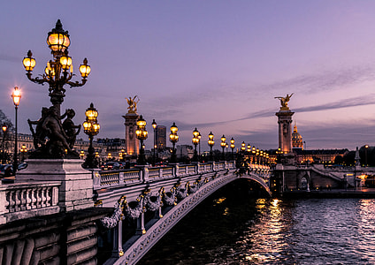 lighted street lamps on bridge over body of water