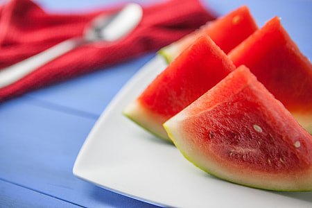 Fresh slices of water melon fruit sit on a blue tabletop, image captured with a Canon DSLR