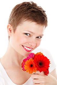 woman holding pink and orange gerbera flowers