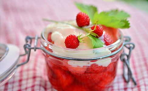 strawberry filled with cream on clear glass bowl