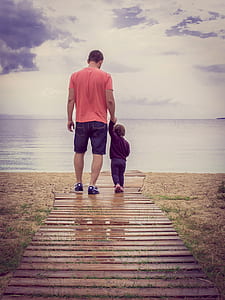 father and child walking on wooden dock