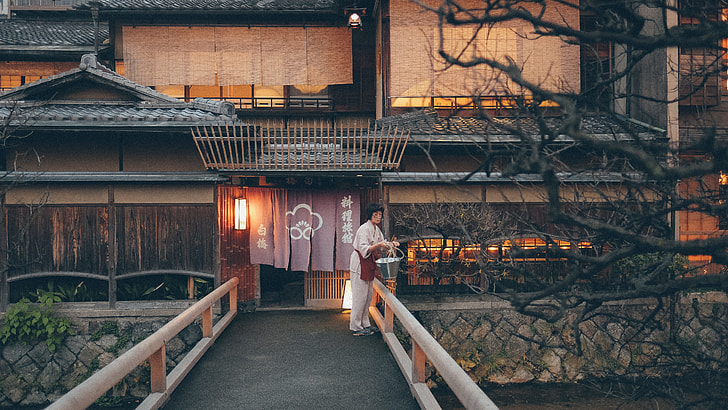 Japanese wooden house with woman in white clothes near river and bridge