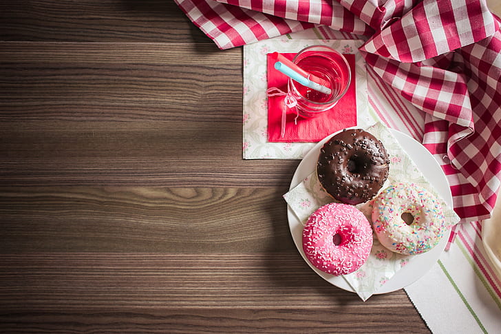 three doughnut place on white ceramic plate beside clear glass cup filled with water