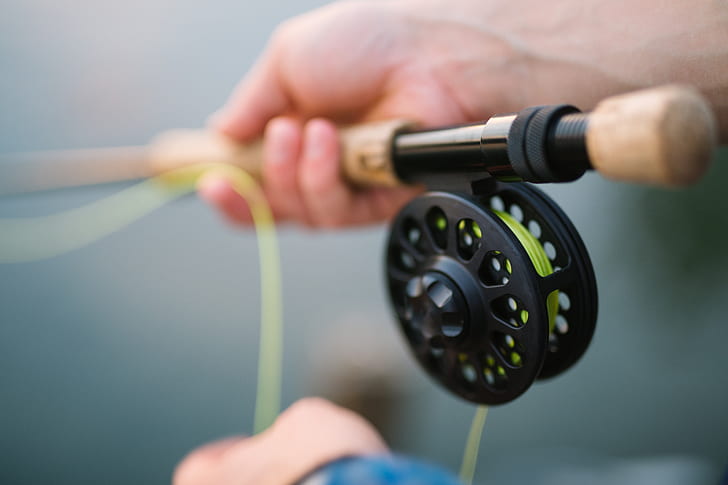 shallow focus photography of a person holding brown fishing rod