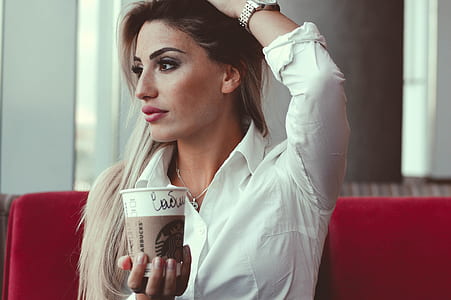 woman in white dress shirt holding a Star Bucks coffee cup