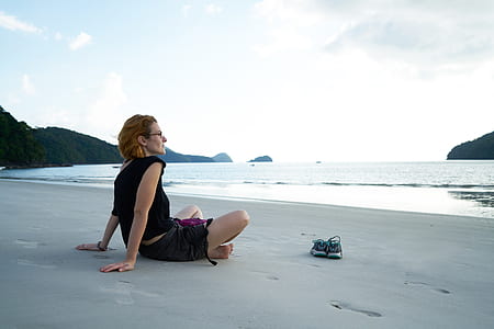 woman sitting on gray sand near the sea