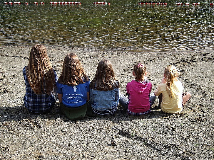 five girls sitting on seashore