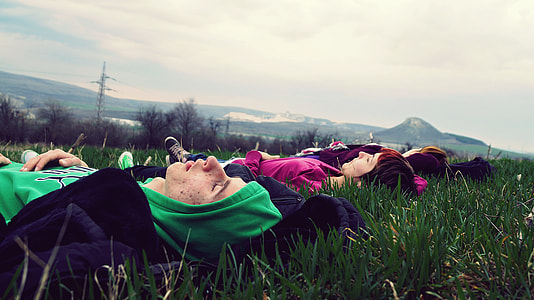 four person laying on a green grass field