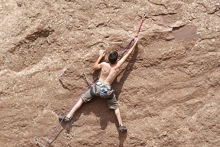 topless man climbing wall
