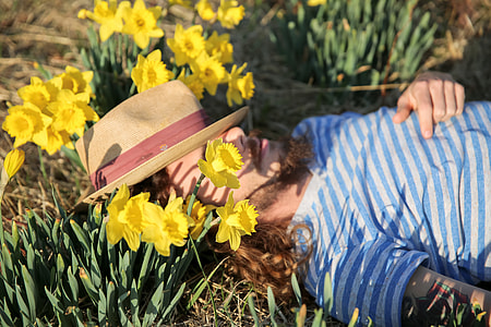 A man wearing a hat lying down amongst flowers