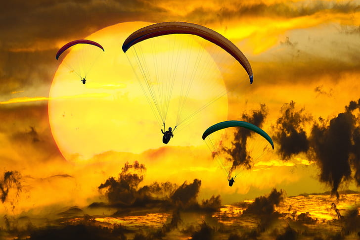 three person parachute against sun