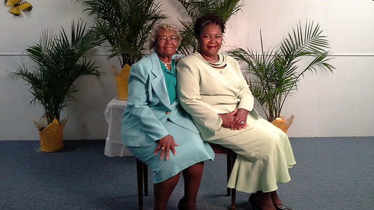 two women in blue and white dresses sitting on brown chair