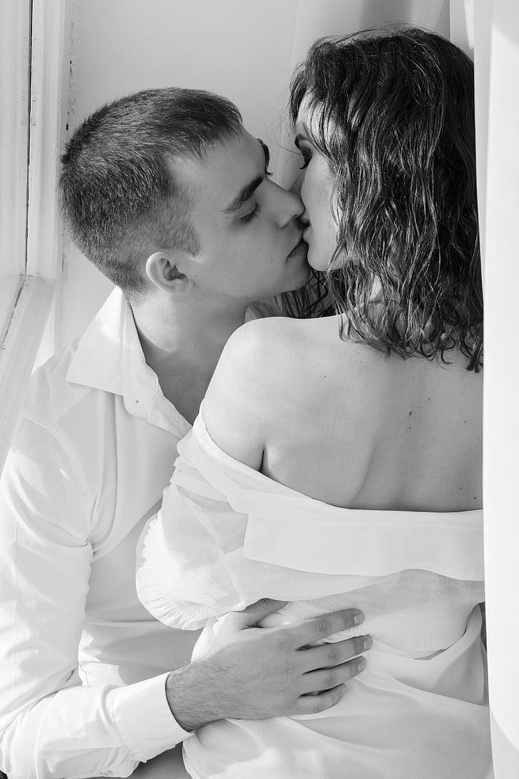 grayscasle photo of woman and man kissing
