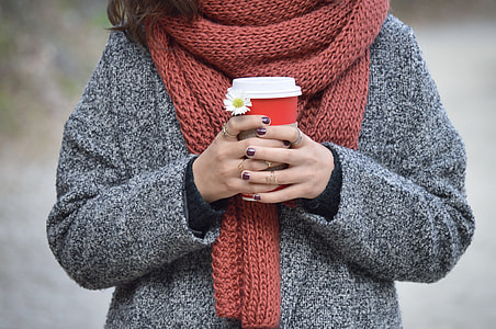 woman wearing gray jacket with brown scarf holding red and white cup