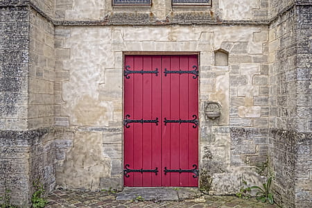 gray brick structure with red wooden door