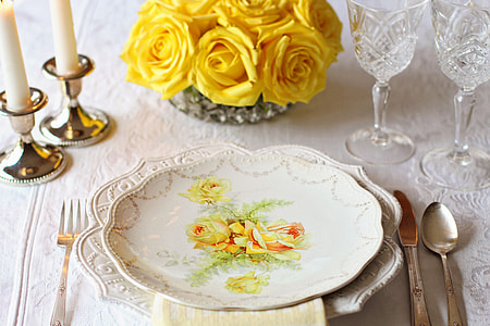 white and yellow floral ceramic plate near butter knife and spoon table setting