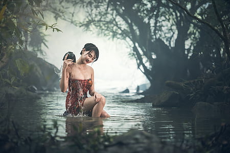 woman wearing maroon and red strapless dress taking a bath on river