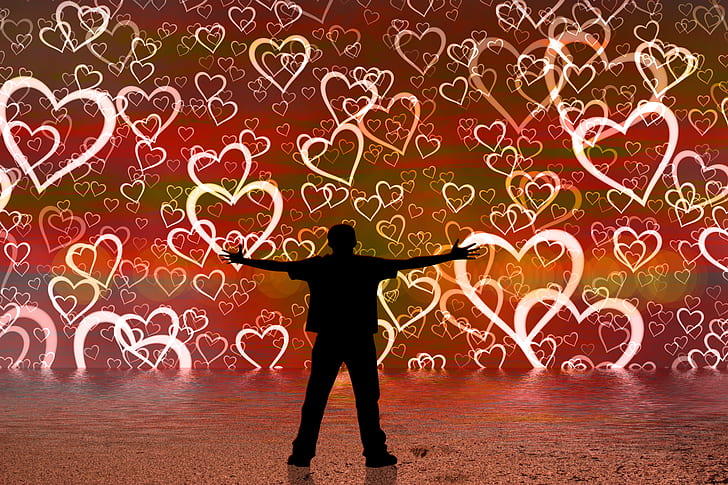 silhouette of man spreading his hands with heart-printed background