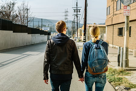 man and woman standing on side of street holding hands
