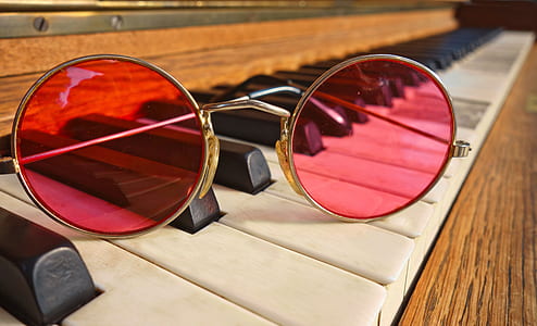 red round sunglasses with gold-colored frame on top of brown piano