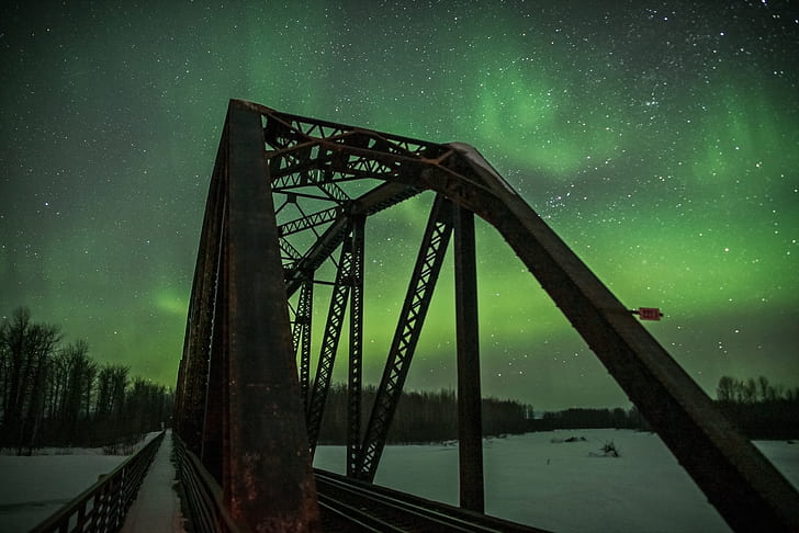 photography of bridge during green sky phenomenon