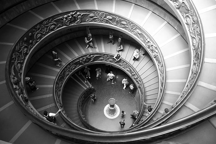 gray scale photography of group of people in twirl staircase