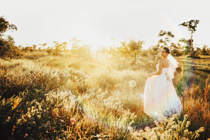 photo of bride standing on brown grass field