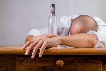 man leaning on desk while holding bottle