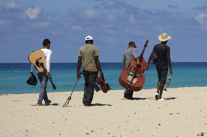 people carrying instruments on beach