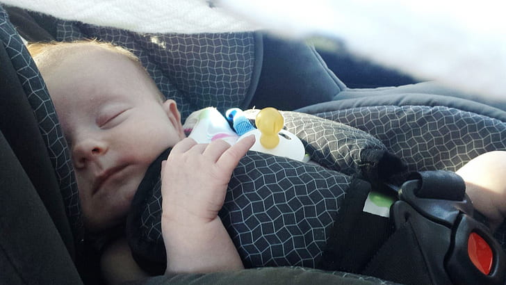 baby sleeping on grey vehicle booster seat