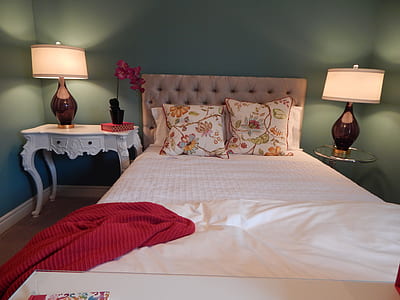 bed with red blanket on the side and table lamps turned on