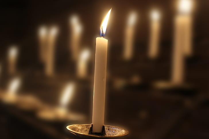 lighted white candle on grey candle holder