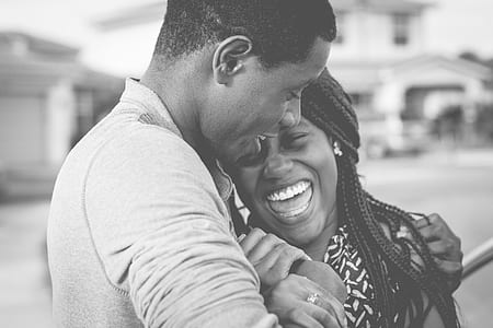 grayscale photo of man hugging woman laughing each other
