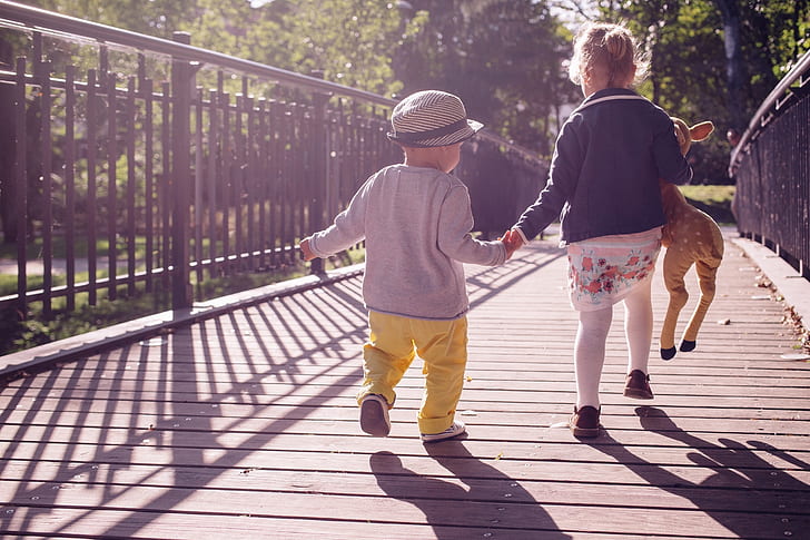 two children walking along a wooden bridge