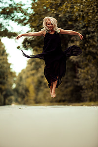 woman wearing black sleeveless long dress while leaping