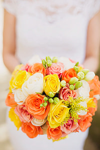 woman wearing white cap-sleeved dress holding yellow-orange-and-white rose bouquet
