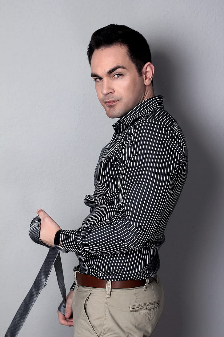man in black and white pinstripe dress shirt holding black leather strap