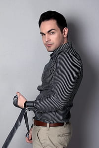 man in black and white pinstripe dress shirt holding black leather strap