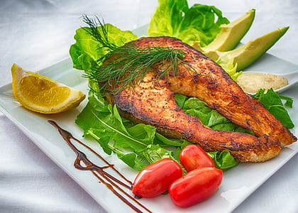 cooked fish on plate with side dish