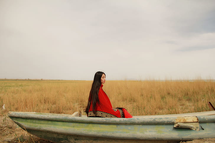 woman wearing red and brown cover sitting on boat