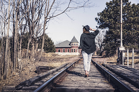 woman wearing black jacket walking on railway